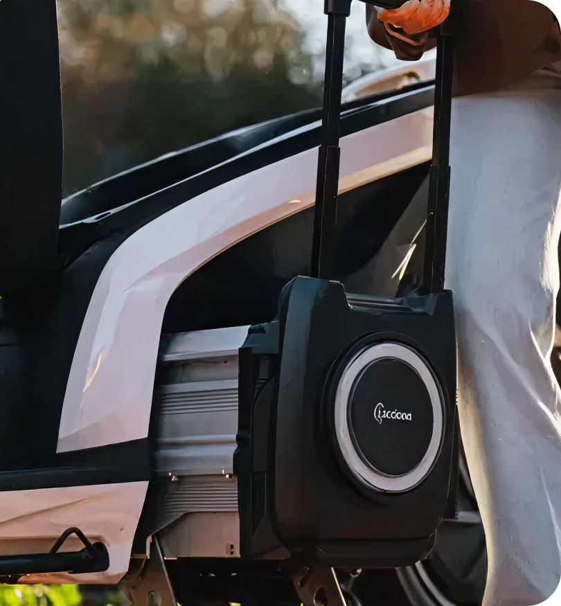 Close-up of a portable black battery pack with a retractable handle attached to a vehicle.