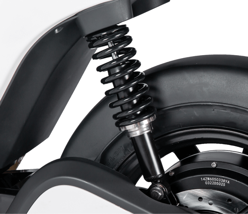 Close-up of black coil spring suspension and rear wheel of an electric scooter or bike.